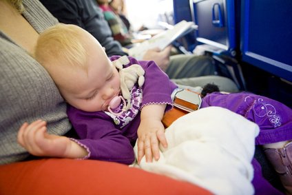 Schlafendes Baby mit Loop Belt auf Schoß im Flugzeug