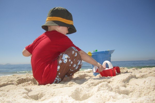 Sonnenbad ohne Konsequenzen: Kind mit Sonnenschutzbekleidung am Strand
