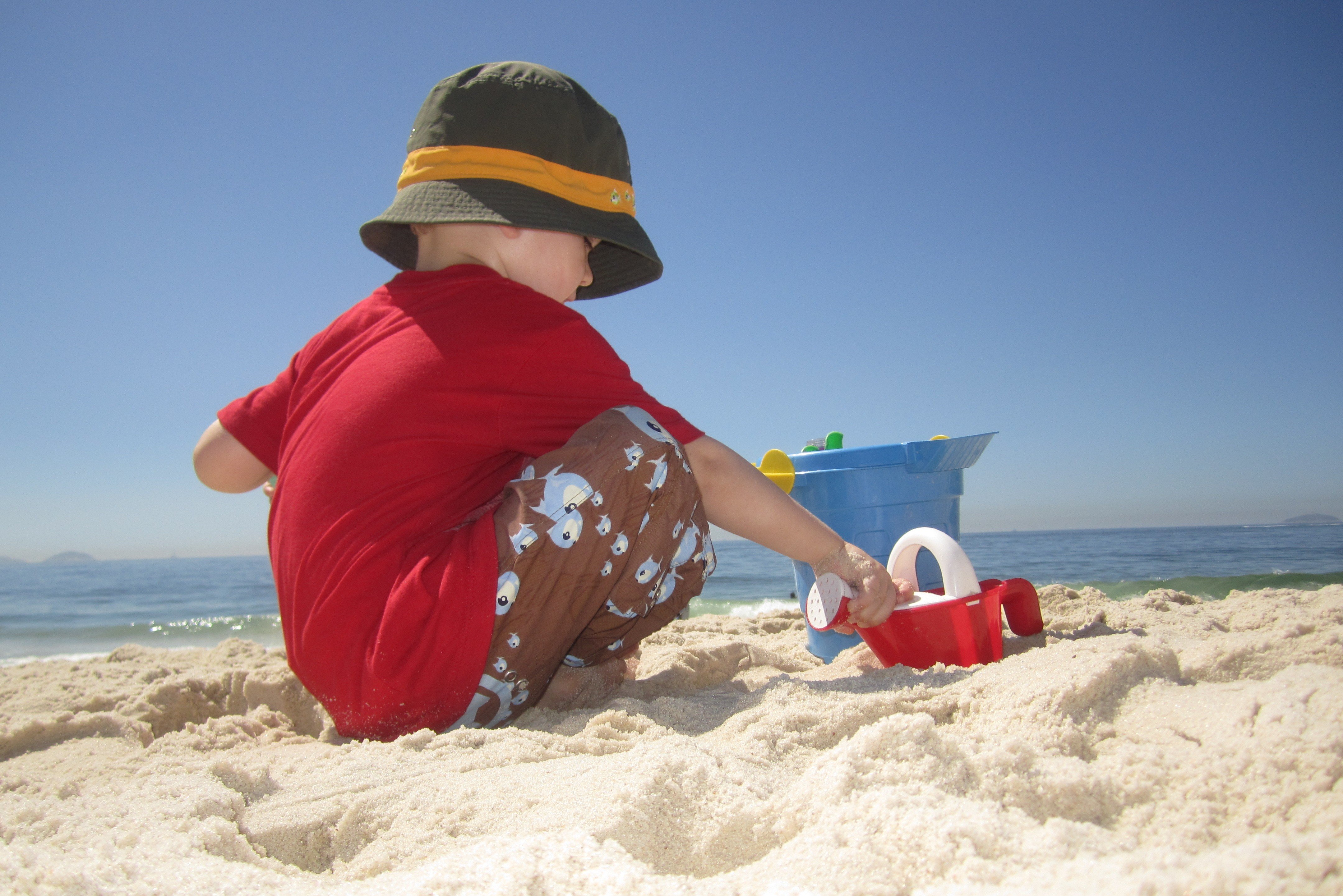 Sonnenbad ohne Konsequenzen: Kind mit Sonnenschutzbekleidung am Strand