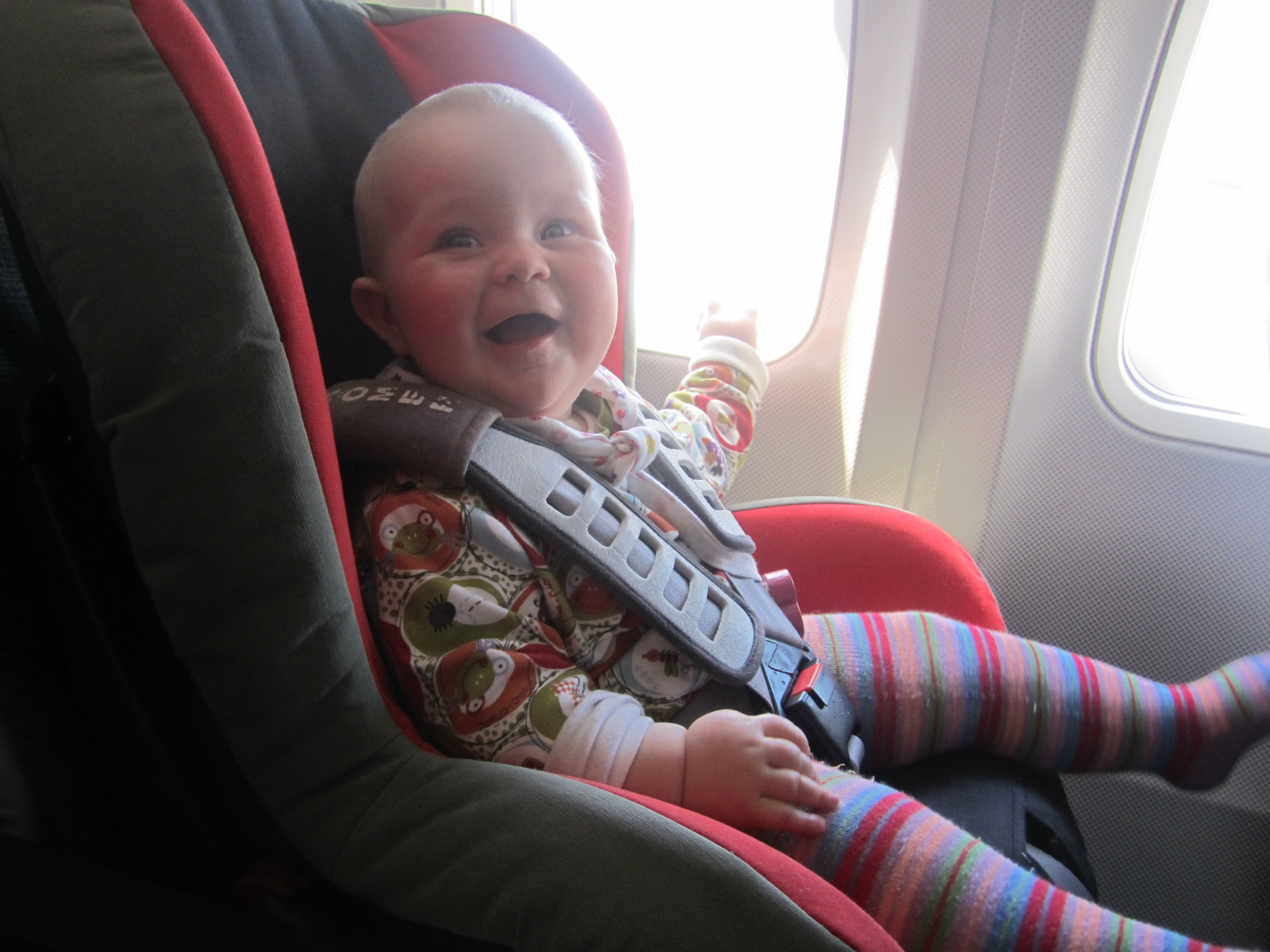 Zufriedenes Baby im Autokindersitz im Flugzeug © KidsAway